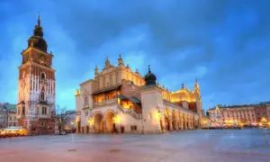 Wieczorny rynek główny Kraków. Sukiennice i wieża ratuszowa oświetlone, niebo granatowe.