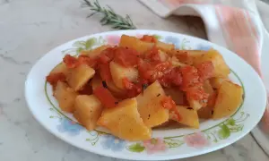 Patate in umido con pomodoro e rosmarino, un piatto semplice e gustoso, servito su un piatto fiorato.
