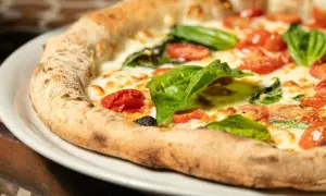 Pyszna pizza Margherita, klasyk kuchni włoskiej, z pomidorkami, mozzarellą i bazylią. Idealna pizza wlochy.