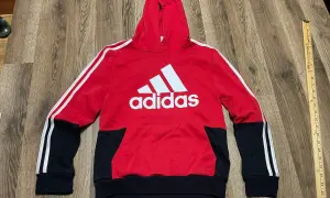 Czerwona bluza z kapturem Adidas dla chłopca z białym logo i czarnymi wstawkami.