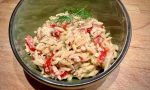 Ein köstlicher Risoni Salat mit Tomaten, Gurken und Feta, garniert mit frischem Dill.