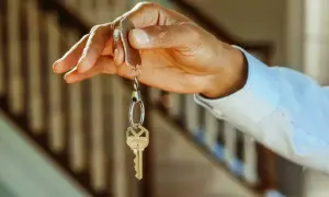 Chiave di casa tenuta in mano, simbolo di un immobile intestato ad un solo coniuge in comunione dei beni.