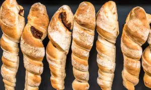 Goldbraunes Stockbrot ohne Hefe, mit dunkler Füllung, auf schwarzem Hintergrund.