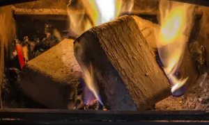Holzbriketts brennen im Kaminofen. Sie glühen und erzeugen Wärme, während die Flammen tanzen.
