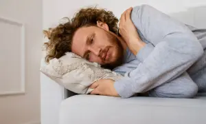 Uomo con capelli ricci e barba sdraiato su un divano, che riflette sulla necessità di esercizi per superare l'agorafobia.