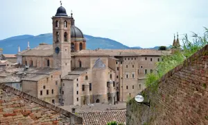 La maestosa corte di Urbino, con il suo campanile e la cupola, si staglia contro le colline.
