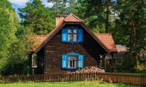 Drewniany dom z niebieskimi okiennicami, idealny na wypoczynek z podlaskim bonem turystycznym 2026.