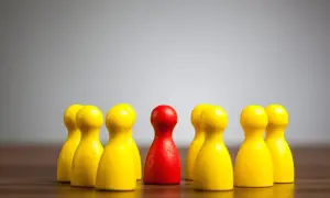 Czerwony pionek otoczony przez żółte, symbolizujące dyskryminację w pracy.