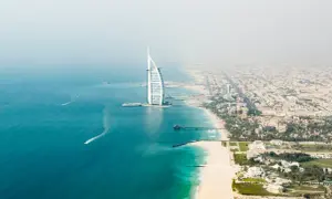 Widok z lotu ptaka na plaże w Dubaju, z charakterystycznym hotelem Burdż al-Arab i turkusową wodą.