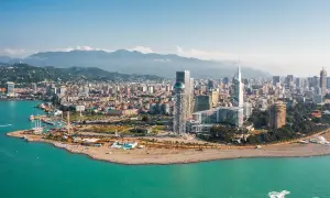 Widok na nowoczesne budynki Batumi i turkusowe morze. W tle góry, idealny batumi klimat do wypoczynku.