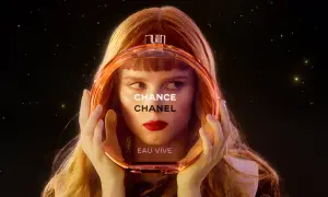 Kobieta z rudymi włosami trzyma okrągłą butelkę perfum Chanel Chance Eau Vive.