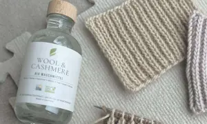 Flasche "Wool & Cashmere" Bio-Waschmittel neben gestrickten Proben. Ideal für die Frage: Pullover waschen welches Programm?