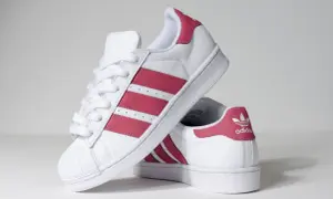 Białe buty Adidas Superstar z różowymi paskami i logo.