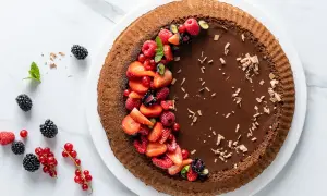 Torta Lindt al cioccolato fondente, decorata con fragole, lamponi, ribes e mirtilli. Un capolavoro goloso.