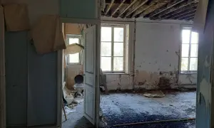 Intérieur délabré d'une maison abandonnée dans les Ardennes, avec un papier peint déchiré, un plafond effondré et une vieille cuvette de toilette. Urbex Ardennes.
