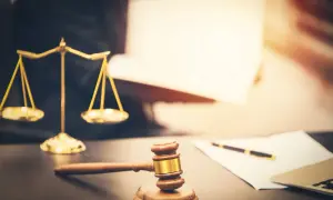 Młotek sędziowski i waga sprawiedliwości na biurku. Rozstrzyganie spraw spadkowych, w tym zachowek po dziadkach, wymaga wiedzy prawniczej.