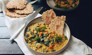 Un plat réconfortant de lentille corail recette, garni de persil frais et servi avec des galettes croustillantes.