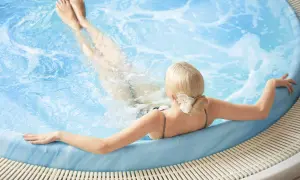 En gravid kvinna njuter av ett varmt bad i en jacuzzi, med benen uppsträckta i det bubblande vattnet.