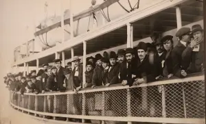 Une foule d'immigrants, hommes et garçons, sur le pont d'un navire, attendant d'arriver à Ellis Island.