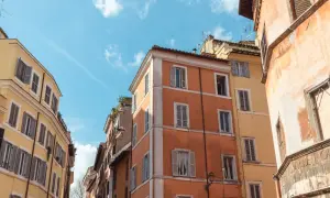 Edifici color pastello a Roma, con persiane chiuse. Il loro valore di un immobile inagibile è incerto, ma il fascino storico rimane.