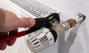 Hand uses pliers to heizungsventil tauschen. Der Thermostatkopf ist auf Stufe 3 eingestellt.