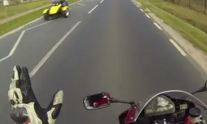 Pozdrowienie motocyklistów na drodze. Żółty pojazd trójkołowy mija motocyklistę.