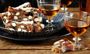 Panforte-bitar med mandlar och torkad frukt, pudrade med florsocker, serveras med ett glas gyllene likör. Ett härligt panforte recept att njuta av.