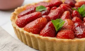 Une tarte aux fraises généreuse, garnie de fruits rouges brillants et de feuilles de menthe. Un délice qui promet la meilleure tarte aux fraises du monde.