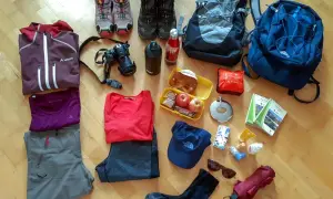Packliste Wanderurlaub: Wanderschuhe, Rucksäcke, Kleidung, Kamera, Verpflegung und Karten für ein Abenteuer in den Bergen.