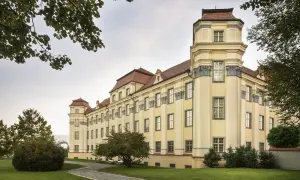 Das neue Schloss Tettnang erstrahlt in hellem Gelb mit roten Dächern. Ein Weg führt durch den gepflegten Garten.