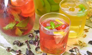 Kall iste med mynta och citron, perfekt för ett iste recept. Torkade hibiskusblommor och jasminblommor ligger utspridda.