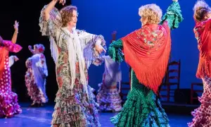 Dos mujeres bailan sevillanas, con volantes y mantones, evocando el origen de esta danza.