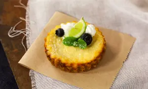 Deliciosa torta de ricota, decorada con arándanos, menta, crema y una rodaja de lima.