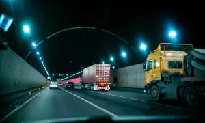 Camion jaune et conteneur dans un tunnel éclairé. La circulation suit la réglementation poids lourd.