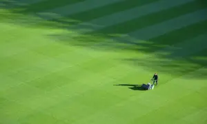 Greenkeeper praca: mężczyzna kosi trawnik na boisku sportowym, tworząc idealne pasy.
