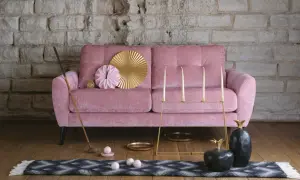 En rosa, **ergonomisk soffa** med dekorativa föremål som en golfklubba, ljusstakar och ananasskulpturer.