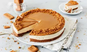 Ein köstlicher Lotus Cheesecake mit Karamellglasur und Keksbröseln. Ein Stück wurde bereits entnommen.