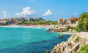 Słoneczne bułgaria plaże z turkusową wodą, kamienistym wybrzeżem i kolorowymi budynkami na wzgórzu.