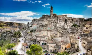 Matera, najstarsze miasto we Włoszech, z kamiennymi domami wciśniętymi w zbocze wzgórza pod błękitnym niebem.