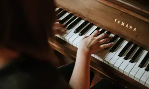 Dłonie dorosłego ćwiczą naukę gry na pianinie Yamaha.