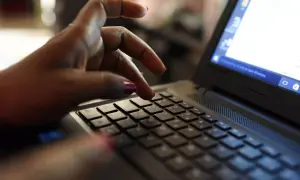 Dłoń z czerwonymi paznokciami pisze na klawiaturze laptopa. Może właśnie wpisuje swój kod podatkowy.