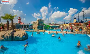 Energylandia wodne atrakcje: ludzie kąpią się w basenie, zjeżdżalnie i roller coaster w tle.
