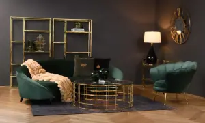Butelkowa zieleń w salonie: aksamitna sofa i fotel, złote regały i stolik kawowy tworzą elegancką całość.