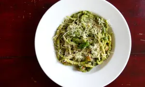 Assiette de trofie au pesto, garnie de parmesan râpé. Une recette italienne savoureuse et colorée.