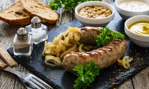 Pyszna biała kiełbasa pieczona w cebuli i musztardzie, podana z chlebem i sosami.