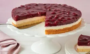 Ein saftiger Kirsch Schmand Kuchen mit einer cremigen Schicht und einem Boden aus Biskuit, bedeckt mit Kirschen in Gelee.