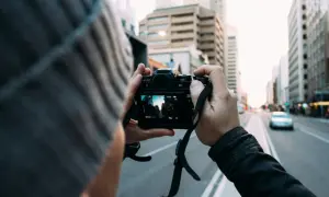Fotografia reportażowa uchwycona przez osobę w czapce, trzymającą aparat i kadrującą miejski krajobraz.