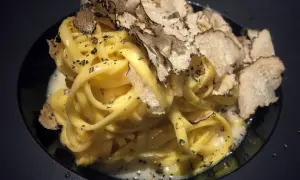 Tagliatelle al tartufo, un piatto elegante con pasta fresca condita con una cremosa salsa e generosamente guarnita con scaglie di tartufo nero.