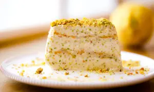 Ein Stück cremiges Semifreddo al Pistacchio, bestreut mit gehackten Pistazien, auf einem Teller.