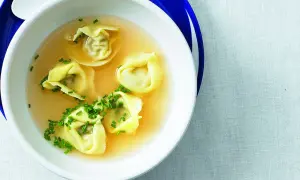 Eine Schüssel mit Tortellini in Brühe, garniert mit Schnittlauch.